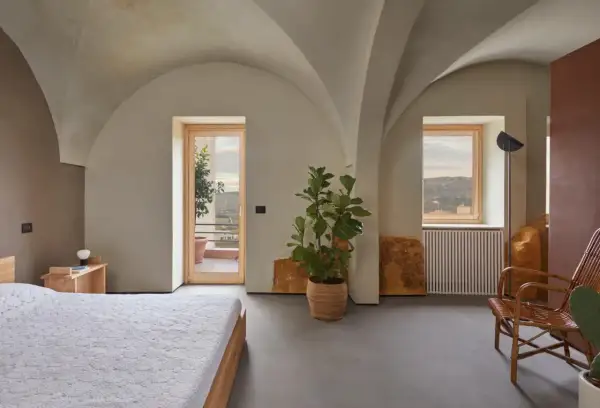 Interno moderno con soffitti a volta, letto, pianta e vista panoramica. Sembra una di quelle case a un euro che diventano gioielli.